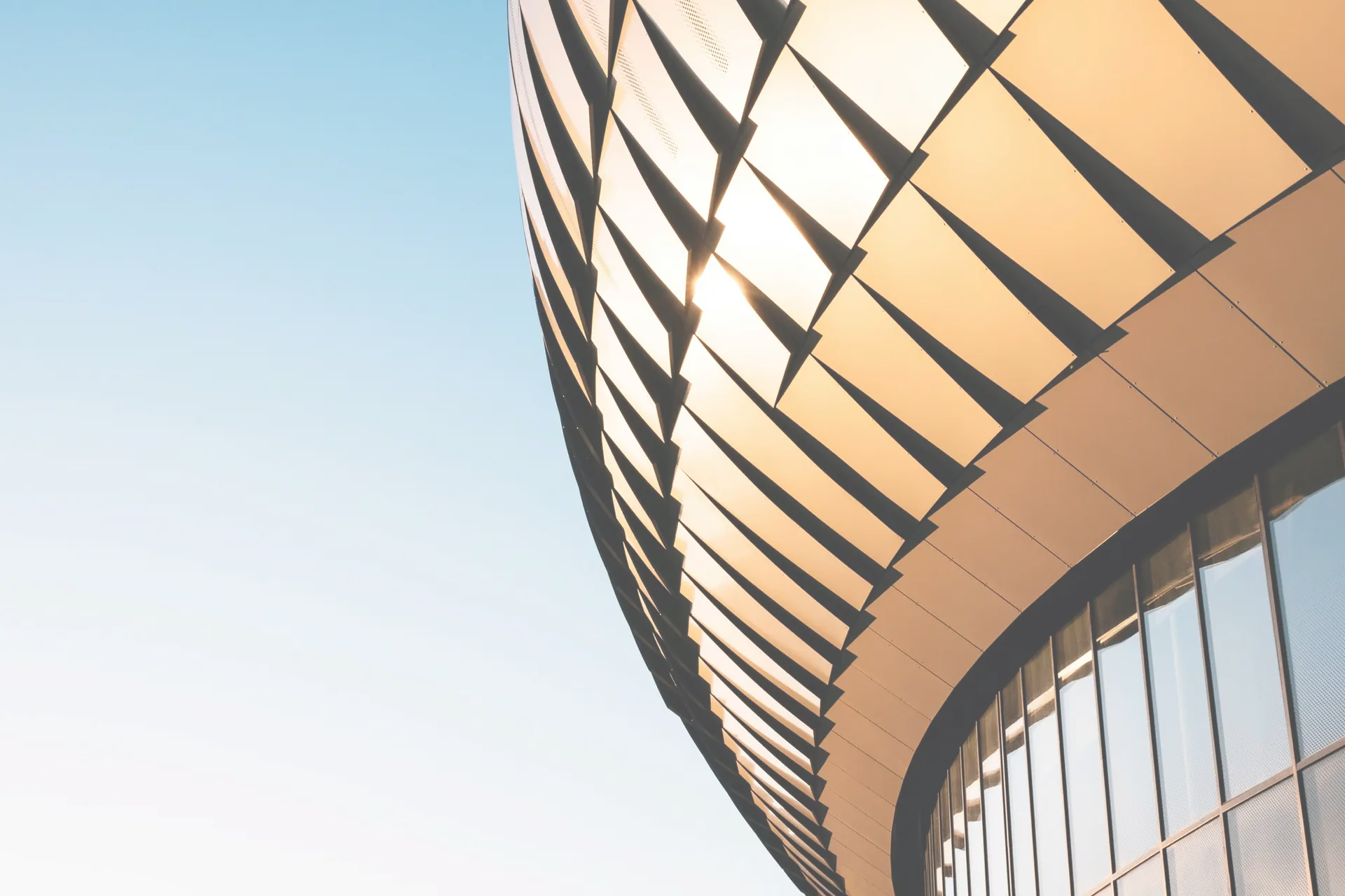 Modern curved façade glowing against a blue sky